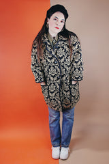 Women's vintage 1960's black and tan tapestry printed button up coat with black leather trim, two front pockets, and a rounded peter pan collar