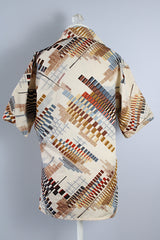 Men's vintage 1970's Jandy Place, Bardon Inc. label short sleeve button up shirt with a pointy collar in a silk like polyester material cream colored with all over brown and blue abstract print.