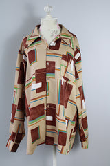 Men's vintage XL 1970's Paul Howard California label long sleeve button up shirt with a pointy collar in a silky soft polyester material with tan, brown, blue, green, and yellow all over abstract print.