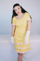 Women's vintage 1960's Miss Elliette California label short sleeve knee length yellow dress with scoop neck and cream floral applique trim.