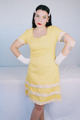Women's vintage 1960's Miss Elliette California label short sleeve knee length yellow dress with scoop neck and cream floral applique trim.