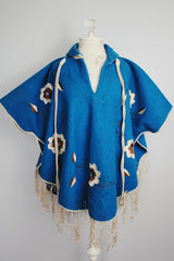 blue wool poncho with white embroidered flowers and white fringe on hem vintage