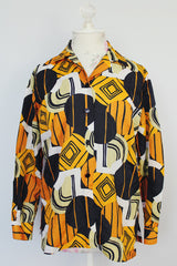 long sleeve button up polyester blouse with double lapel in an abstract orange green and black print 1970's