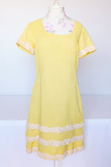 Women's vintage 1960's Miss Elliette California label short sleeve knee length yellow dress with scoop neck and cream floral applique trim.