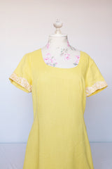 Women's vintage 1960's Miss Elliette California label short sleeve knee length yellow dress with scoop neck and cream floral applique trim.