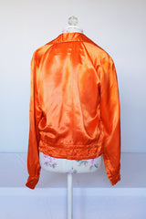 Women's or men's vintage 1940's/1950's long sleeve equestrian racing top in orange satin with one cream vertical stripe.