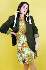 Women's vintage 1960's sleeveless knee length shift dress in off white with an all over floral print and orange trim.