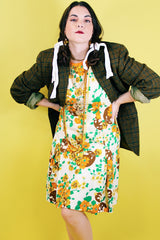 Women's vintage 1960's sleeveless knee length shift dress in off white with an all over floral print and orange trim.