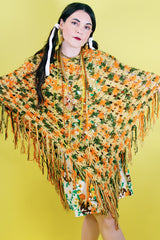 Women's vintage 1970's acrylic knit multicolored poncho with a long fringe trim hem, drawstring at neck, and V shaped neckline in orange, mustard yellow, and olive green colors.