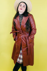 Women's vintage 1970's long length long sleeve leather wrap coat in maroon color. Double lapel, tie belt, pockets.