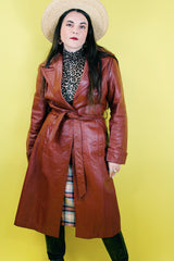 Women's vintage 1970's long length long sleeve leather wrap coat in maroon color. Double lapel, tie belt, pockets.