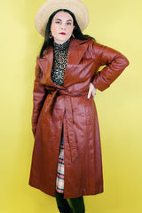 Women's vintage 1970's long length long sleeve leather wrap coat in maroon color. Double lapel, tie belt, pockets.