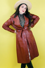 Women's vintage 1970's long length long sleeve leather wrap coat in maroon color. Double lapel, tie belt, pockets.