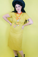 Women's vintage 1960's Jan Sue label short sleeve knee length shift dress in yellow cotton with multicolored floral print stitched on the front.
