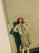 Women's vintage 1960's short sleeve midi length green and white printed wrap dress with two big white buttons at waist.
