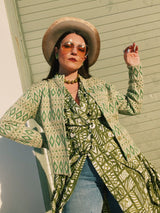 Women's vintage 1960's short sleeve midi length green and white printed wrap dress with two big white buttons at waist.