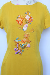 Women's vintage 1960's Jan Sue label short sleeve knee length shift dress in yellow cotton with multicolored floral print stitched on the front.