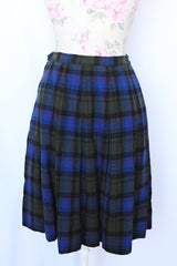 Women's vintage 1970's Lipman's Caliente Shop, Century of Boston label pleated wool knee length skirt in blue, forest green, red, and black plaid print.