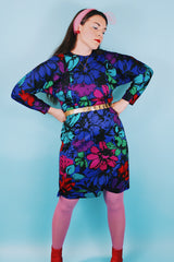 Women's vintage 1980's Blair, Warren, PA label long sleeve mini length polyester material dress in blue, pink, red, and green all over floral print. Dolman fit with elastic waistband.