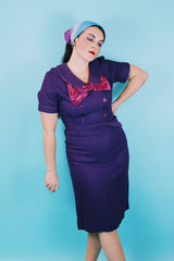 Women's vintage 1960's Mode O'Day label short sleeve knee length purple wool blend dress with peter pan collar, satin bow, matching belt, and decorative buttons.