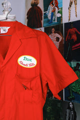 short sleeve red work jumpsuit with collar zips up front and patches on front and back vintage 1970's