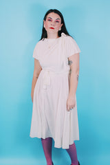 Women's vintage 1970's short sleeve capped sleeved midi length off white cream dress with draped neckline, attached tie bow on shoulder, elastic waistband, and detachable matching tie belt