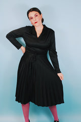 Women's vintage 1970's Joan Curtis long sleeve midi length black dress with pleated accordion skirt, a V shaped neckline, and detachable matching tie belt.
