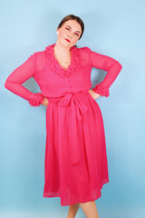Women's vintage 1970's long sleeve midi length bright pink sheer dress with half button closure and ruffle trim around neckline and cuffs.
