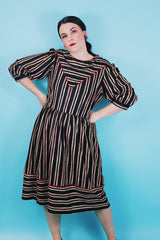 Women's vintage 1980's Walden Classics, Made in USA label 3/4 arm length midi length black striped dress with cinched waist, buttons on shoulders and triangle flap in front and back.