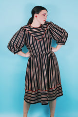 Women's vintage 1980's Walden Classics, Made in USA label 3/4 arm length midi length black striped dress with cinched waist, buttons on shoulders and triangle flap in front and back.