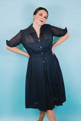 Women's vintage 1950's short sleeve midi length navy blue sheer shirt dress with subtle checkered print.