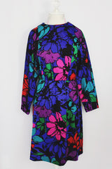 Women's vintage 1980's Blair, Warren, PA label long sleeve mini length polyester material dress in blue, pink, red, and green all over floral print. Dolman fit with elastic waistband.