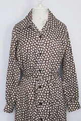 Women's vintage 1970's long sleeve knee length button up shirt dress in brown with all over white floral print.