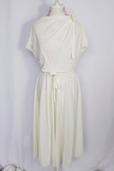 Women's vintage 1970's short sleeve capped sleeved midi length off white cream dress with draped neckline, attached tie bow on shoulder, elastic waistband, and detachable matching tie belt