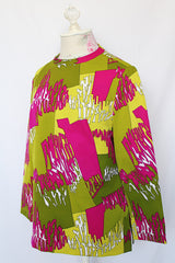 Women's vintage 1970's long sleeve polyester blouse with zipper in the back and darted bust. All over green and purple print