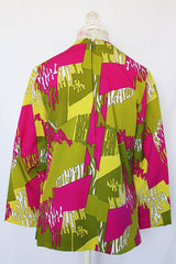 Women's vintage 1970's long sleeve polyester blouse with zipper in the back and darted bust. All over green and purple print