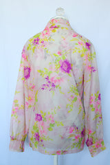 Women's vintage 1970's long sleeve button up blouse with pointy dagger collar. White sheer polyester with all over purple and pink floral print.
