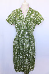 Women's vintage 1960's short sleeve midi length green and white printed wrap dress with two big white buttons at waist.