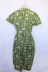 Women's vintage 1960's short sleeve midi length green and white printed wrap dress with two big white buttons at waist.