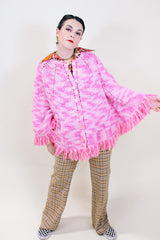Women's vintage 1970's pink colored crochet knit poncho in soft acrylic material. Fringe trim hem and buttons up the front.