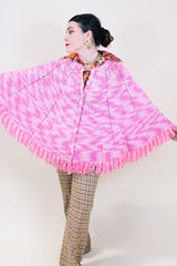 Women's vintage 1970's pink colored crochet knit poncho in soft acrylic material. Fringe trim hem and buttons up the front.