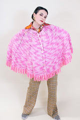 Women's vintage 1970's pink colored crochet knit poncho in soft acrylic material. Fringe trim hem and buttons up the front.
