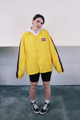 Women's or mens' vintage 1970's Swingster, World of Wearables label long sleeve yellow lightweight windbreaker with popper buttons and a maroon stripe on each arm. Schlitz patch on left chest