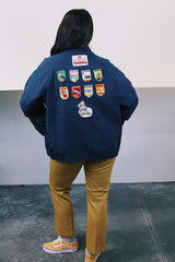 Men's vintage 1980's Lacy Sportswear label long sleeve zip up sportswear windbreaker jacket in navy blue cotton with patches sewn on all over.