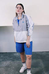 Women's or men's vintage 1980's Nike label long sleeve lightweight pullover windbreaker with a half zip closure in grey, white, and blue.