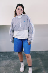 Women's or men's vintage 1980's Nike label long sleeve lightweight pullover windbreaker with a half zip closure in grey, white, and blue.