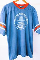 short sleeve blue t-shirt with red and white stripes on arm graphic on front and back vintage 1970's