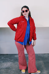 Women's vintage 1970's Pla-Jac by Dunbrooke, Made in USA label long sleeve red nylon windbreaker with popper buttons, cotton liner, round collar, and white graphic.