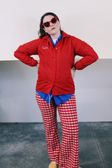 Women's vintage 1970's Pla-Jac by Dunbrooke, Made in USA label long sleeve red nylon windbreaker with popper buttons, cotton liner, round collar, and white graphic.