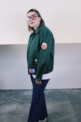 Women's or men's vintage 1980's Riverside Flexbac, Made in USA label long sleeve green zip up station jacket with patches all over. Has collar and pockets.